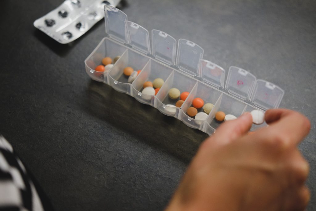 A close-up shot of a person neatly organizing their medicines in a medicine organizer.