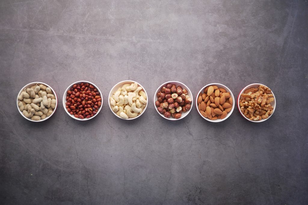 An aesthetic display of various nuts, neatly arranged in small white bowls.