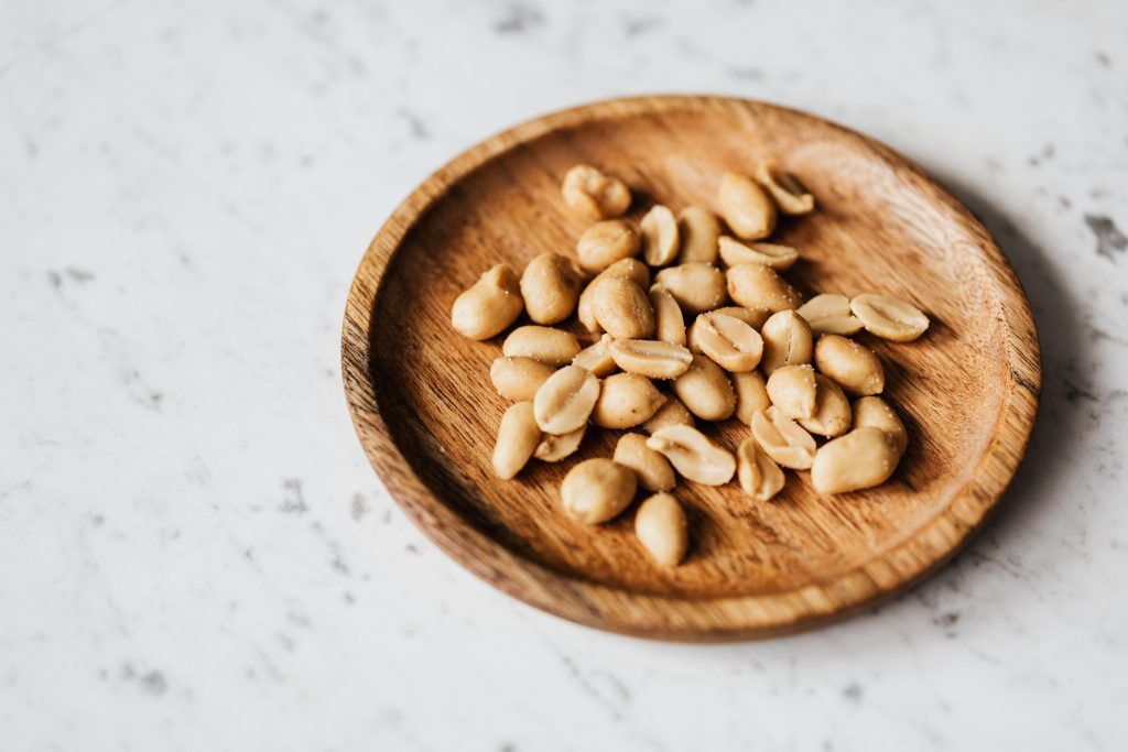 Salted peanuts, a potential food allergen that may contribute to brain fog, placed in a wooden bowl.