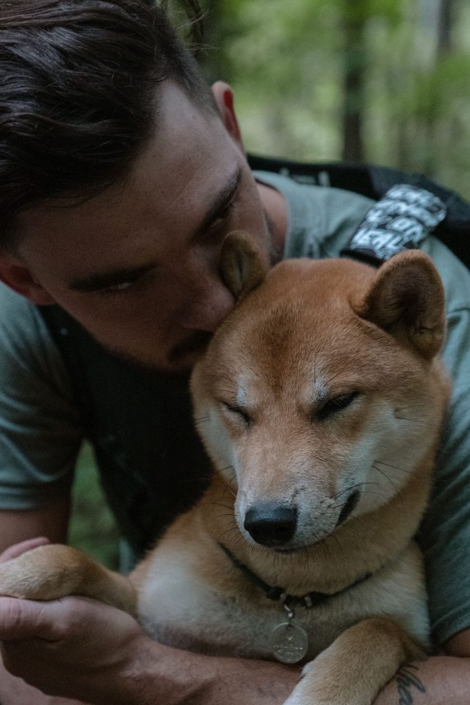 A candid shot of a man gently hugging his beloved pet dog, showcasing their strong emotional bond.