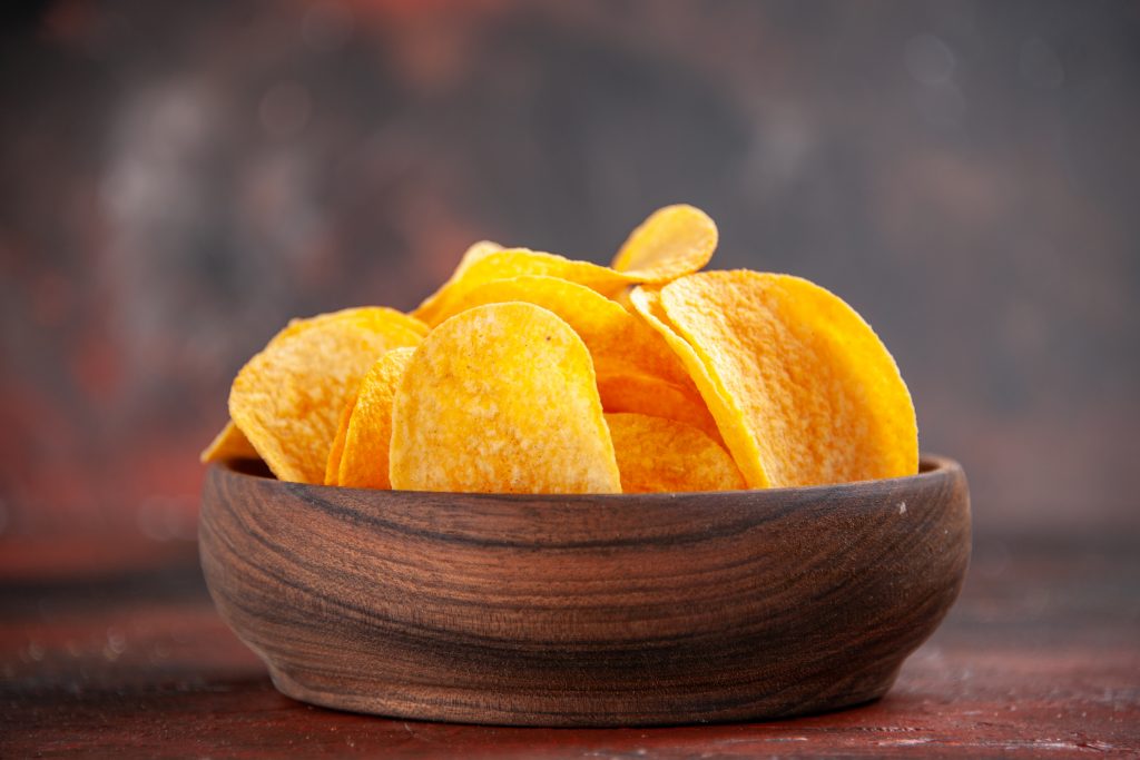 A wooden bowl of potato chips, a reminder to skip the pre-dinner nibble basket for healthier eating choices.