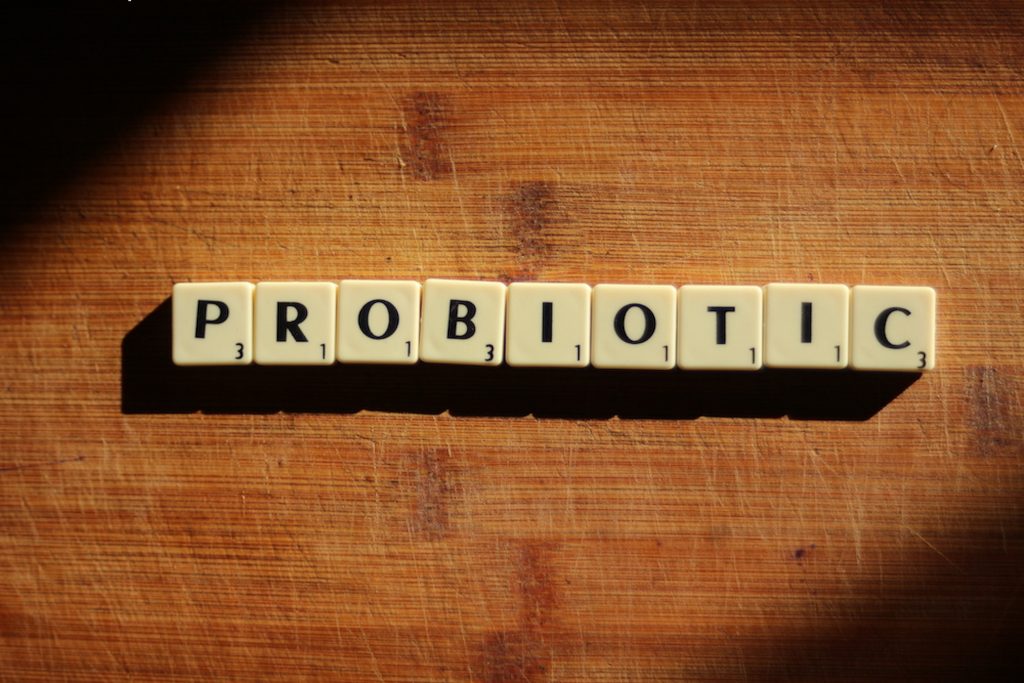 An illuminated view of 'PROBIOTIC' spelled with Scrabble tiles on a wooden table.