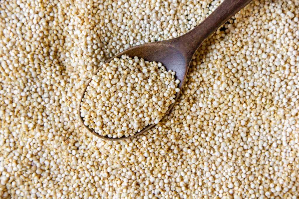 A close-up shot of quinoa being scooped with a wooden spoon.