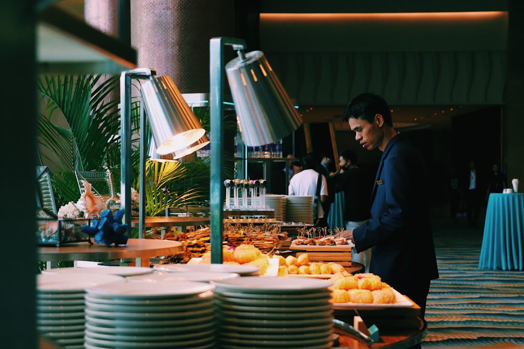 Buffet setup with warm lighting, fresh pastries, and a staff member, highlighting the challenge of eating the right amount with unlimited food.