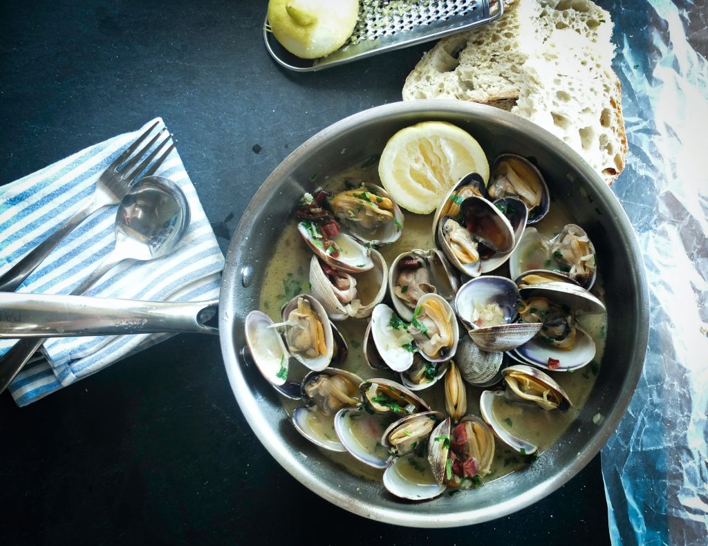 A sumptuous-looking clam dish, rich in vitamin B-12, presented on a table alongside a fresh loaf of bread.