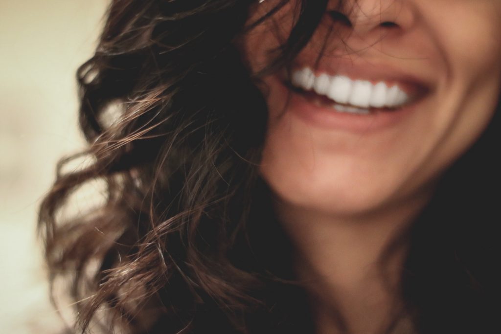 A candid close-up shot of a woman smiling happily, showcasing her pearly white teeth.