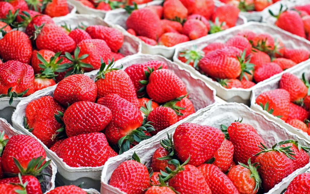 A visually appealing shot of strawberries packed in plastic boxes, neatly stacked horizontally.
