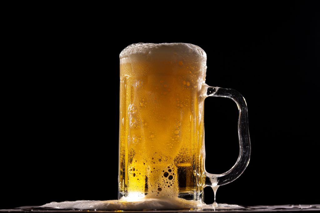 A glass of beer with foam, illustrating that drinking too much can contribute to weight gain around the belly.