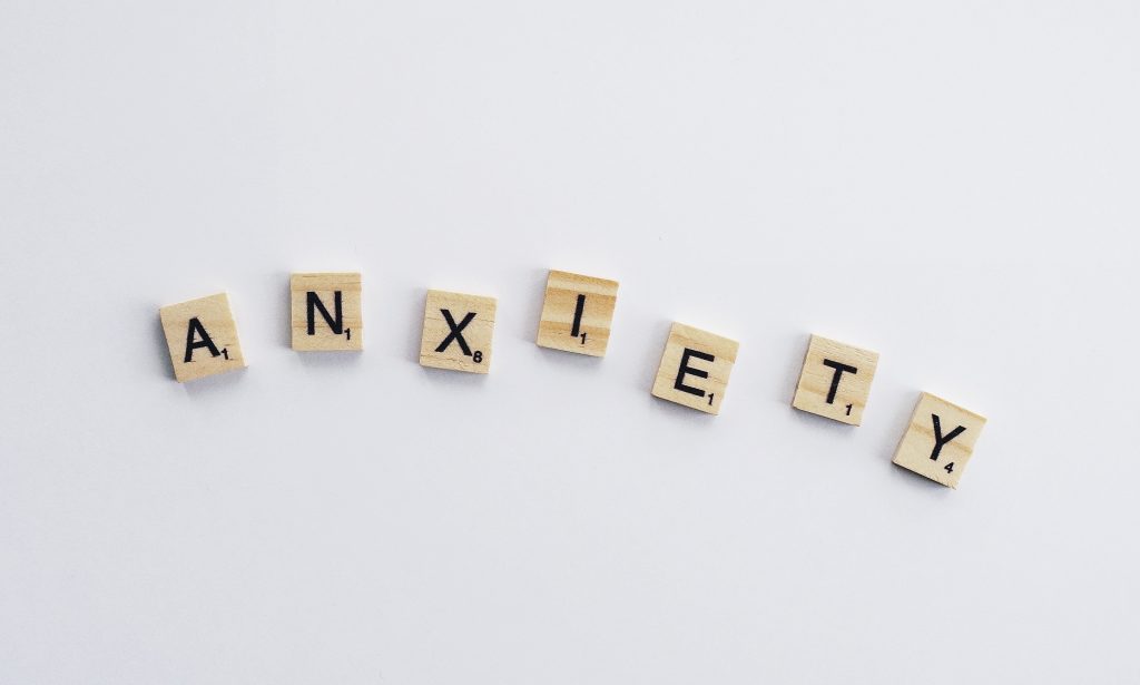 Scrabble tiles spelling 'ANXIETY' on a white background, highlighting anxiety as a symptom of hypothyroidism.