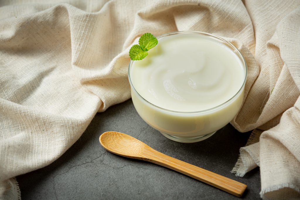 Creamy milk in a glass with a mint leaf garnish, high in protein and calories, next to a wooden spoon on a cloth.