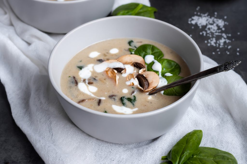 A white bowl of soup garnished with fresh spinach, symbolizing healthy lifestyle tips for weight reduction.