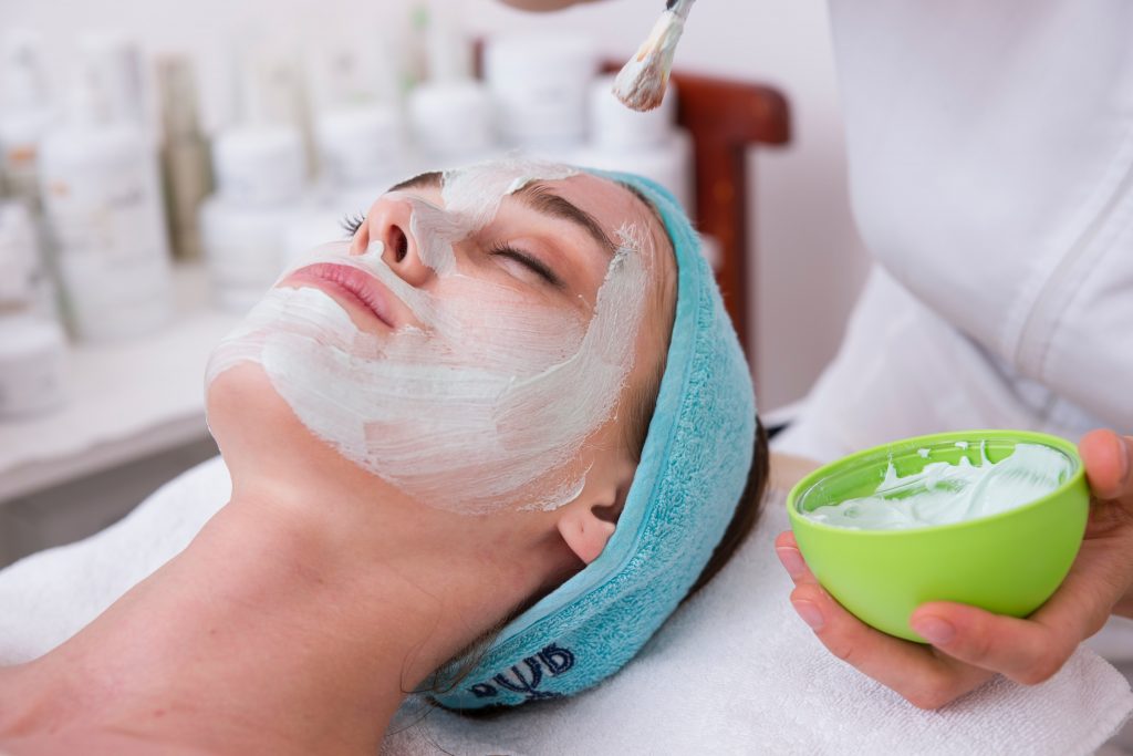 A professional applies a facial mask to a woman, representing a simple and balanced approach to a slimming lifestyle.