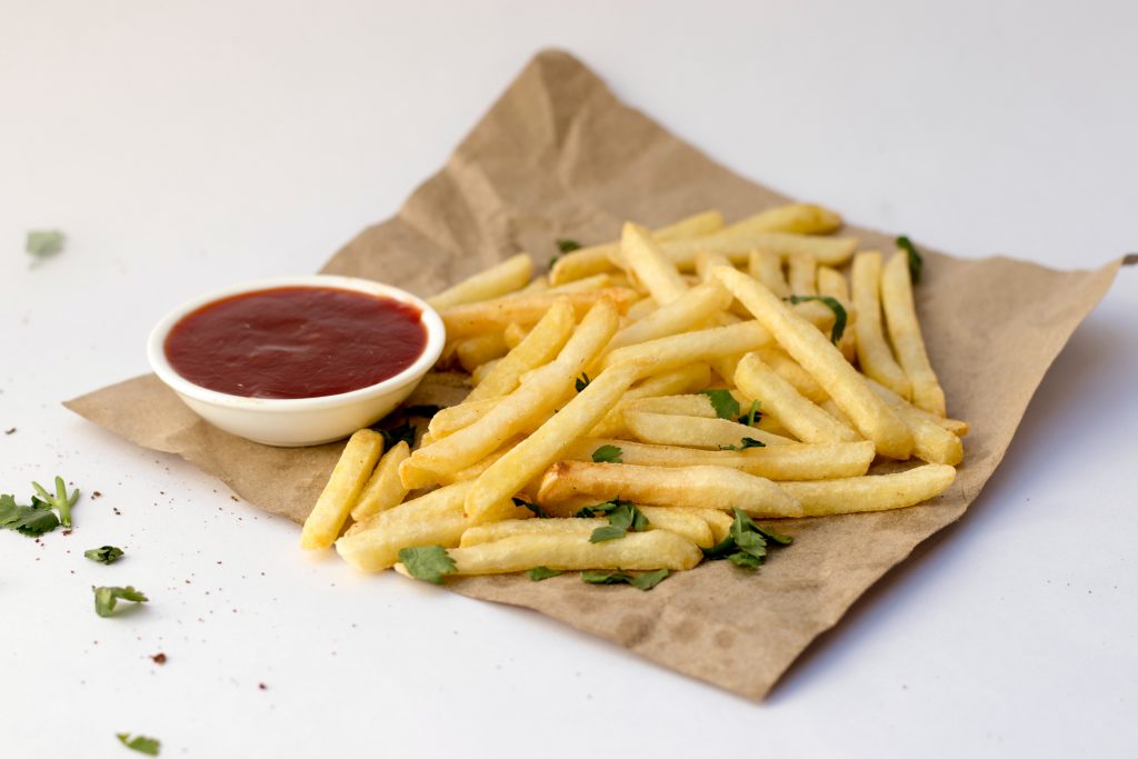 French fries with ketchup and parsley, reminding us that too much salt can cause bloating.