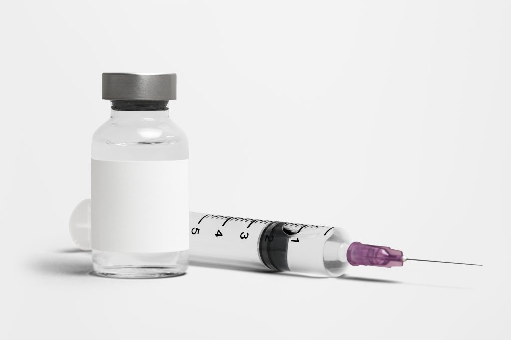 A syringe with a purple cap and medicine bottle, used in the treatment of Vitamin B12 deficiency.