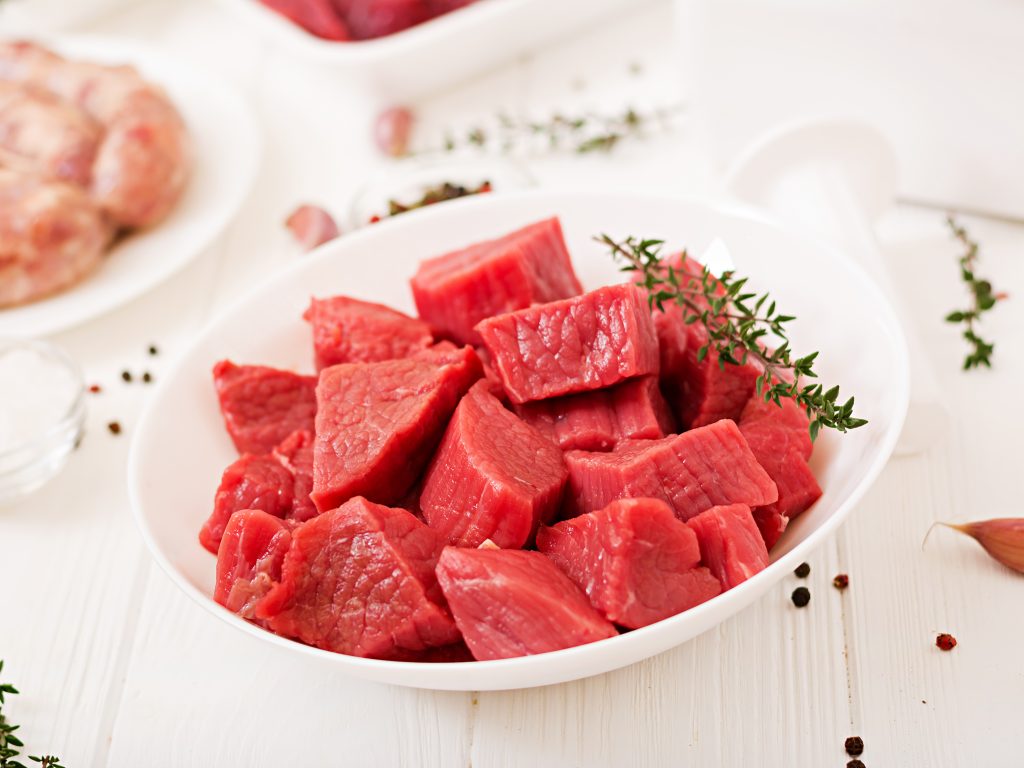 Raw meat cubes in a white bowl, a good source of iron, found in red meat and other nutrient-rich foods.