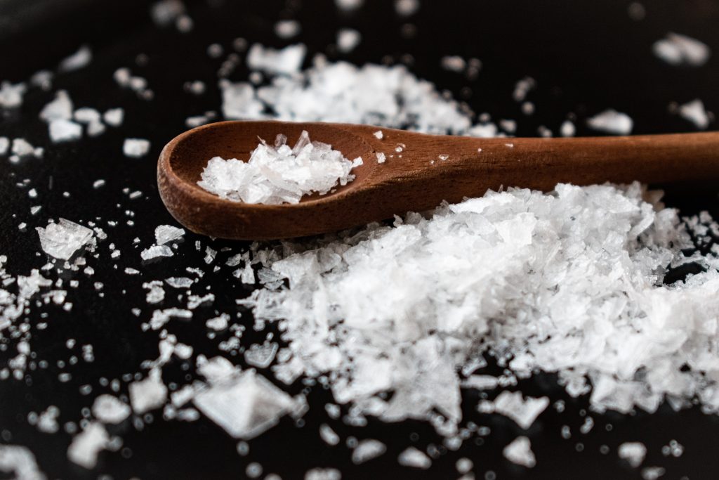 A wooden spoon holding sea salt, rich in iodine, essential for brain and nervous system growth and development.
