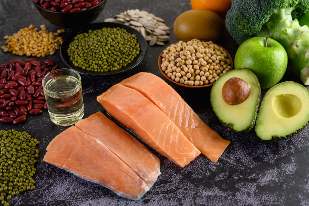 A nutritious display of salmon, avocado, beans, peas, and green apples, perfect for enhancing vitamin D levels through diet.