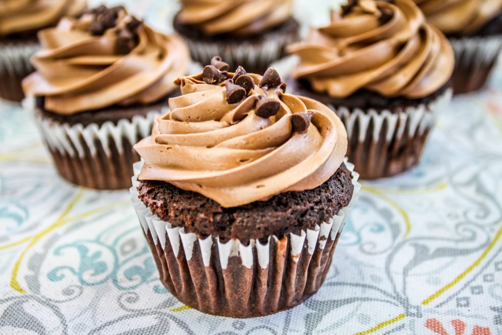 Chocolate cupcakes placed on a decorative cloth, highlighting the need to limit refined carbs to help prevent gout symptoms.