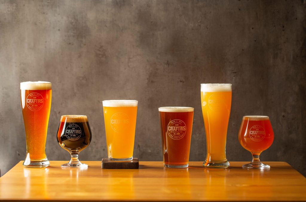 A row of colorful drink glasses on a wooden table, symbolizing purine-rich choices that may elevate uric acid and trigger gout.