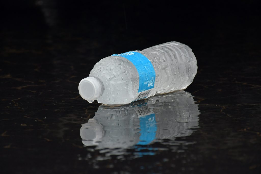 A chilled water bottle on a dark surface, droplets forming on its sides, symbolizing hydration's role in boosting metabolism.