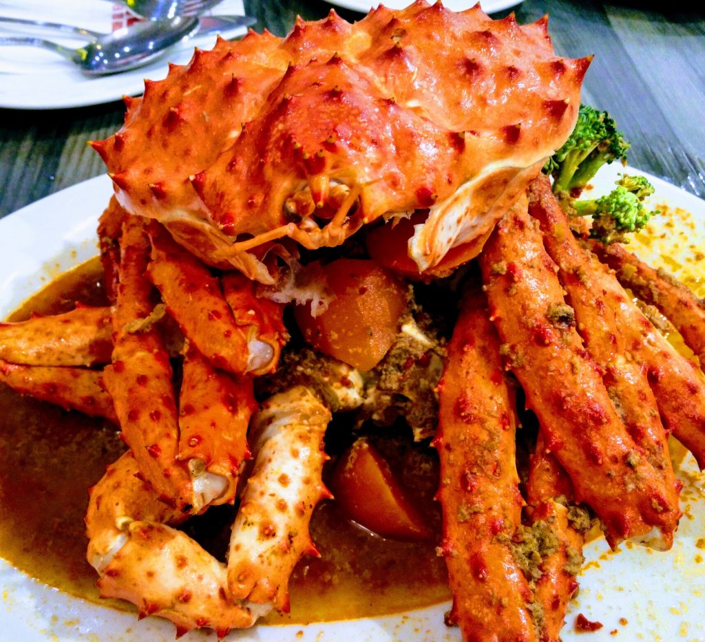 A plate of steamed crab legs with broccoli and yellow sauce, highlighting dietary choices for managing gout effectively.