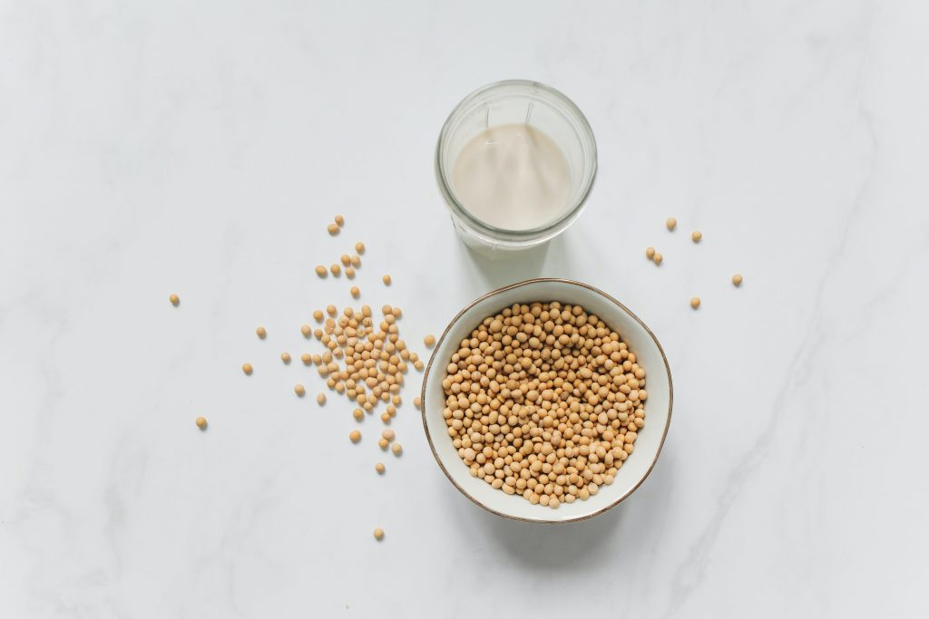 A bowl of soybeans, scattered beans, and a glass of milk, rich in nutrients for a healthy nervous system, skin, and nails.