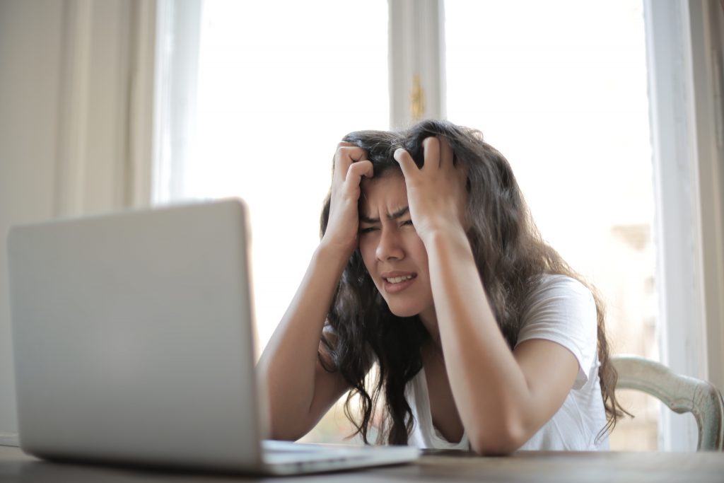 A woman stressed, eating processed food, emphasizing how stress contributes to stubborn belly fat.