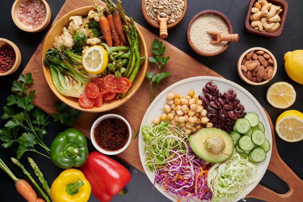 A wooden cutting board with two plates of salad, vegetables, nuts, and grains, showcasing the Mediterranean diet's balanced portions.