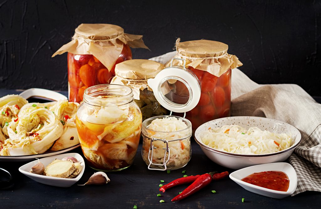 Fermented and pickled foods in jars, highlighting the benefits of probiotics for managing PCOS symptoms.