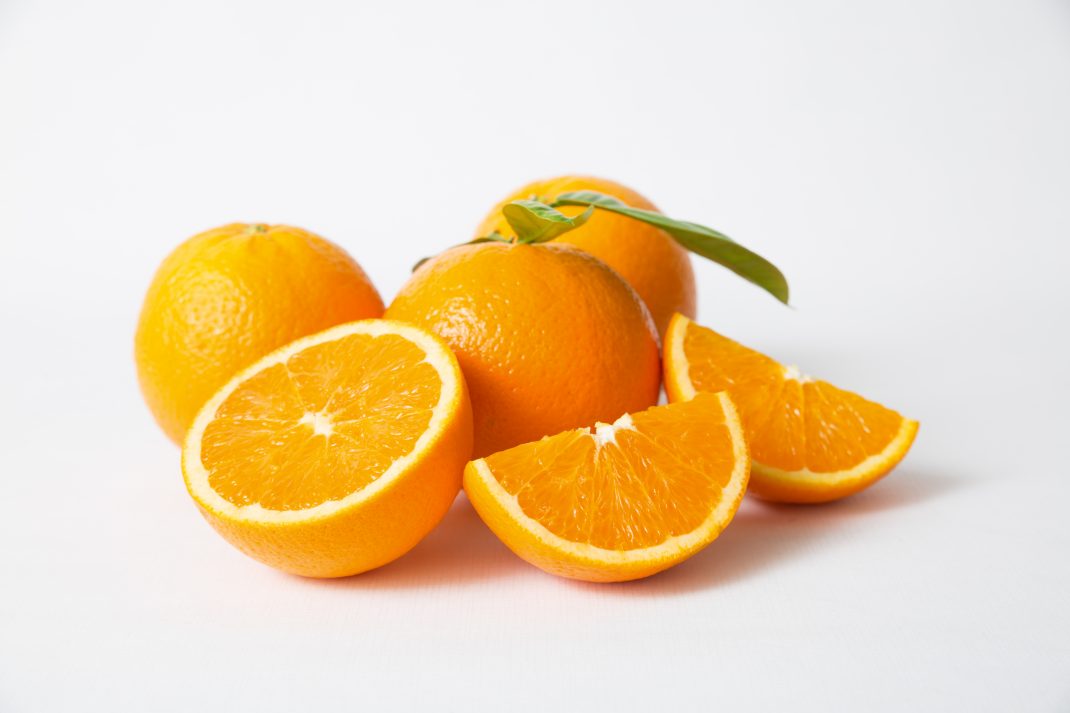 Whole oranges and a cut orange, highlighting their role in boosting iron absorption and protecting against iron deficiency anemia.