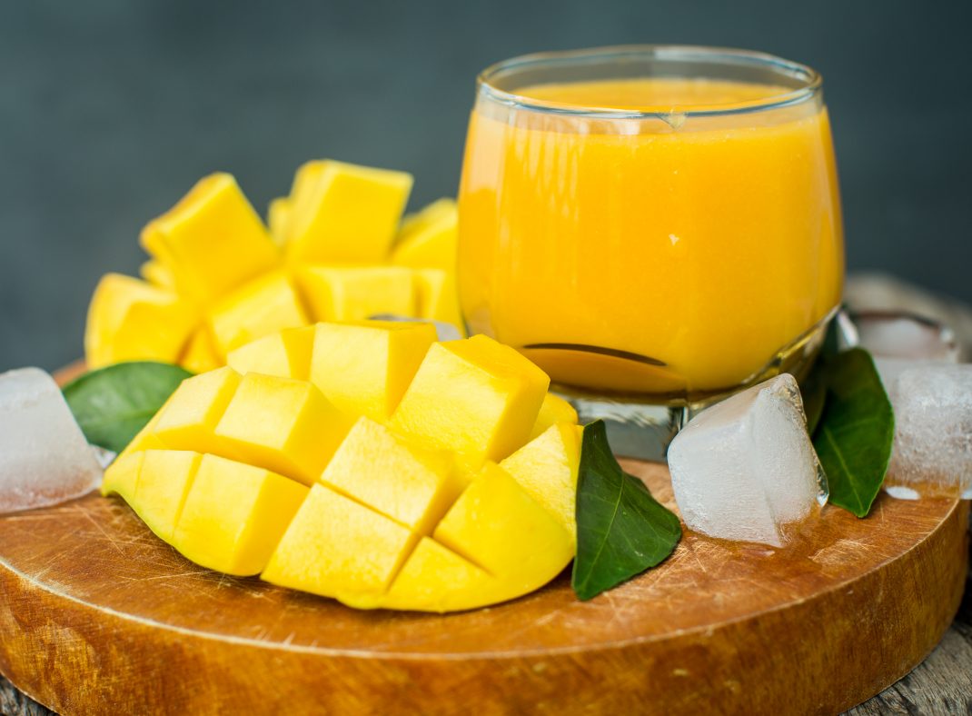 Fresh diced mango with mango juice, garnished with ice cubes and leaves, rich in vitamins A & C, potassium, and fiber.