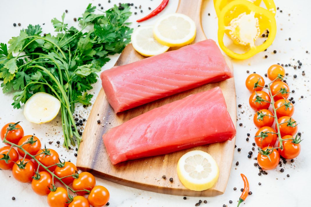 Fresh fish steaks with cherry tomatoes, lemon slices, and parsley, highlighting magnesium-rich and nutritious foods.