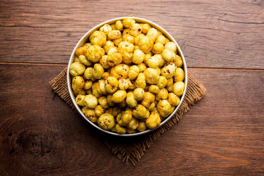 A bowl of roasted makhana under a jute mat, a great low-carb, high-fiber, and protein-rich snack for healthier choices.
